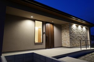 スロープ、石張り外壁、間接照明を施した玄関アプローチ